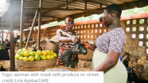 Togo woman with mask sells produce on street, credit Lina AyabaCARE