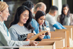 Diverse adults packing donation boxes in charity food bank by SDI Productions from Getty Images Signature