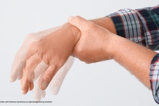Hands of Mature Man with Parkinson Syndrome on Light Background by pixelshot